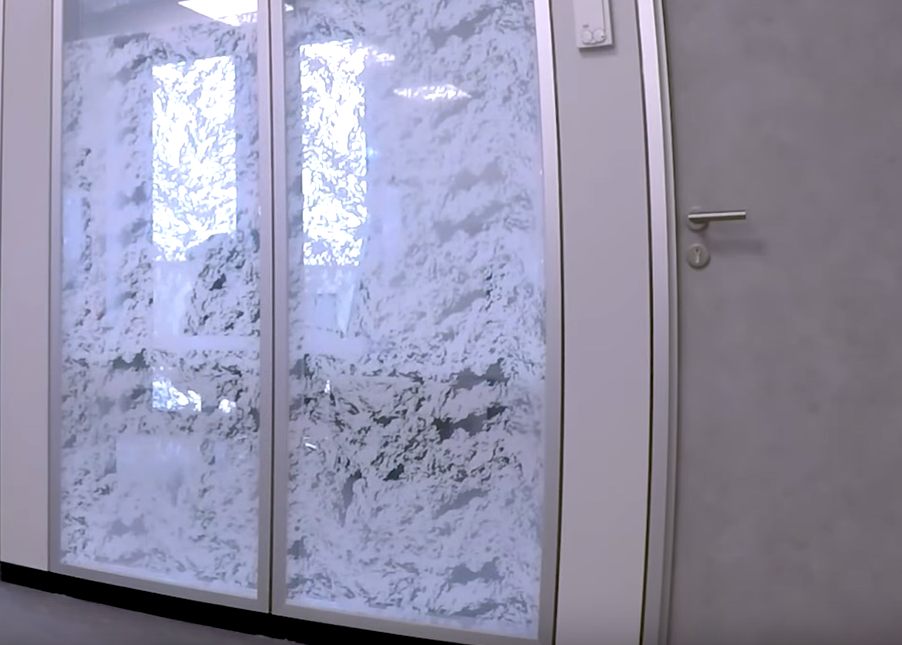La même porte vitrée après pose d'un film dépoli à motif irrégulier : la lumière passe, la vue est masquée