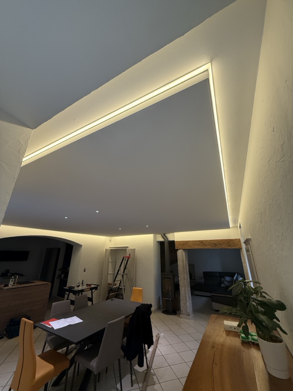 Plafond tendu acoustique blanc mat avec ruban LED en pourtour et spots encastrés, dans un séjour à Voiron