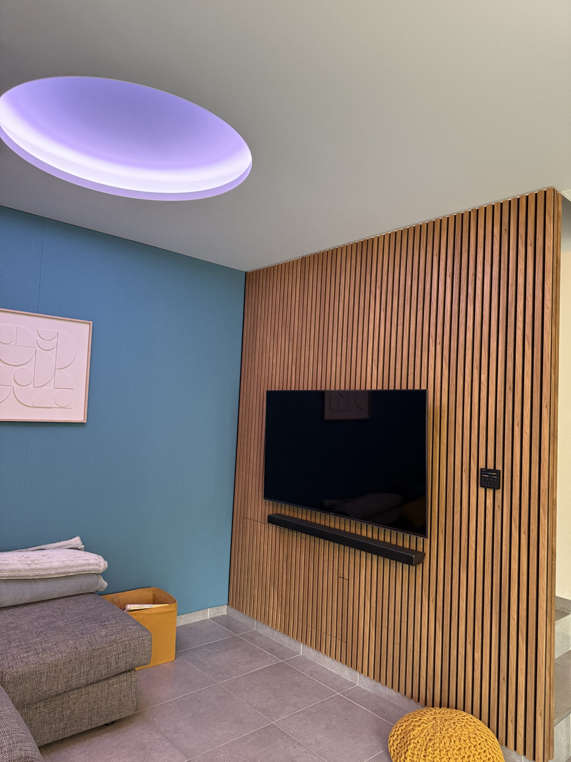 Mur du séjour habillé de panneaux acoustiques bois WoodUpp Akupanel par Textens, téléviseur et barre de son intégrés