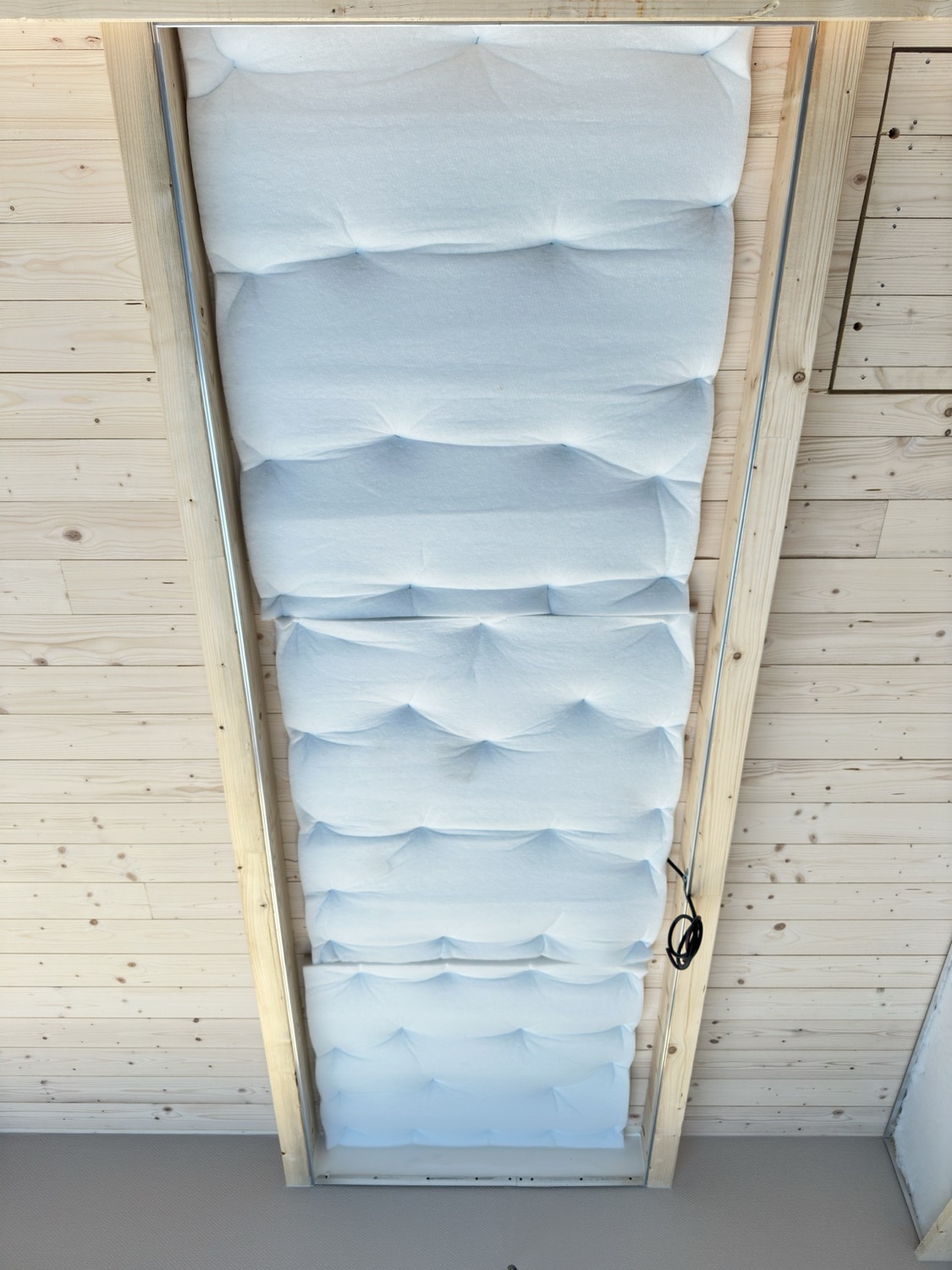 Plafond en lambris clair : le molleton acoustique blanc est visible dans le profilé, avant la pose de la toile tendue